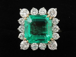 A diamond and emerald cluster ring, the trap cut emerald estimated at 9.99 ct, diamonds 2.20 carats (20,000-26,000).