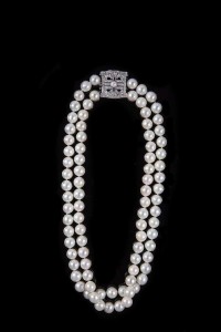 A double row of cultured pearls, of graduated length to an Art Deco diamond and ruby plaque clasp (20,000-40,000).