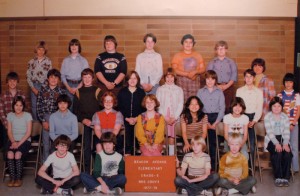 Curt Cobain: A color photograph of Kurt Cobain, later of the band Nirvana, in his fifth grade group class photo. Cobain, with his blond hair, is seen sitting on the floor holding one side of a red sign that reads, Beacon Avenue Elementary Grade - 5 Mrs. Grove  (200-300)