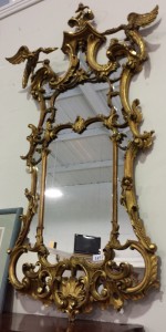 A Chippendale tradition carved wood cartouche shaped mirror with exotic bird mounts.