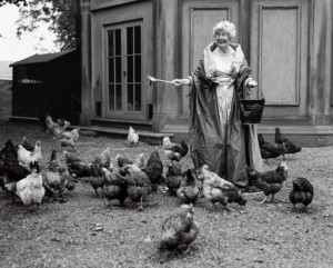 Deborah, Duchess of Devonshire feeding her chickens at Chatsworth, 1995 wearing a Balmain ball gown and pearls. Copyright Bruce Weber